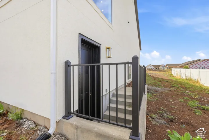Exterior wall with stucco finish, black metal railing, and an outdoor light fixture