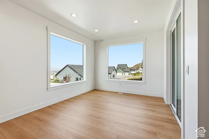 Wood-finish flooring, recessed lighting, and large windows with white trim