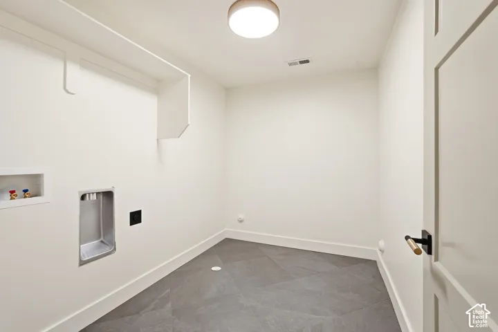 Spacious utility area featuring durable tile flooring, built-in shelving, and a modern flush-mount ceiling light