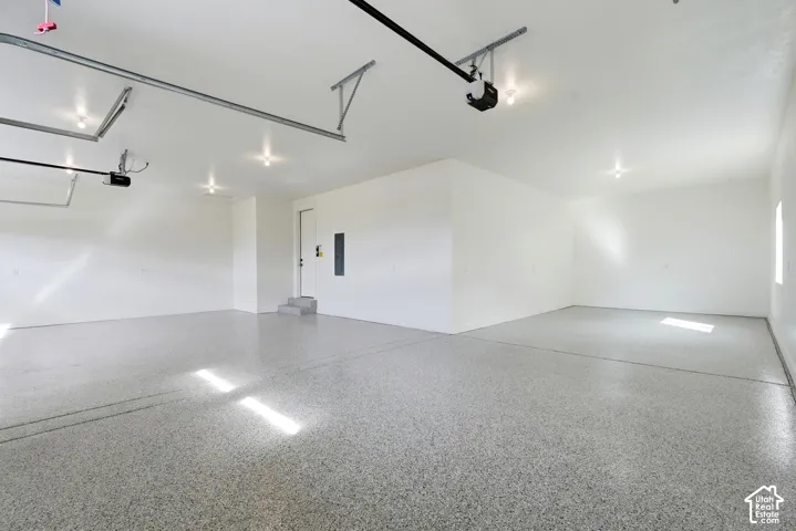 Spacious garage featuring a durable epoxy floor, recessed lighting, and a window for natural illumination