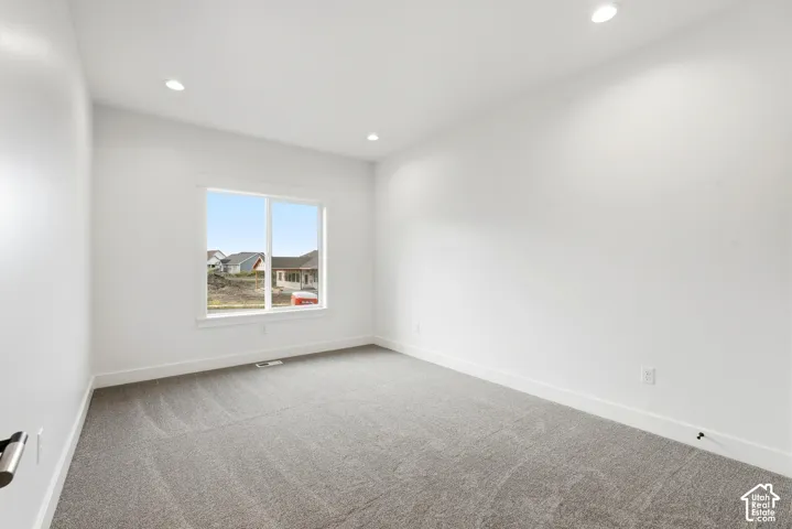 Bright interior with recessed lighting, white walls, and gray carpeting