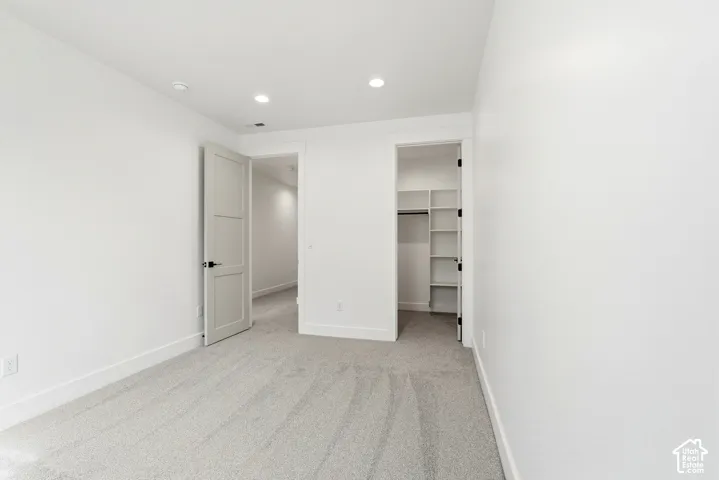 Neutral tone carpeting throughout, recessed ceiling lighting, and a closet with built-in shelving