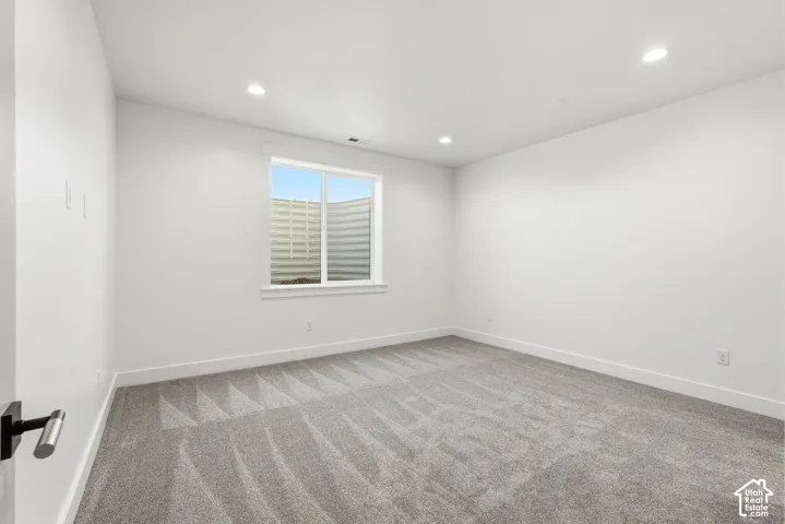 White walls, grey carpeting, a double-paned window, and recessed lighting