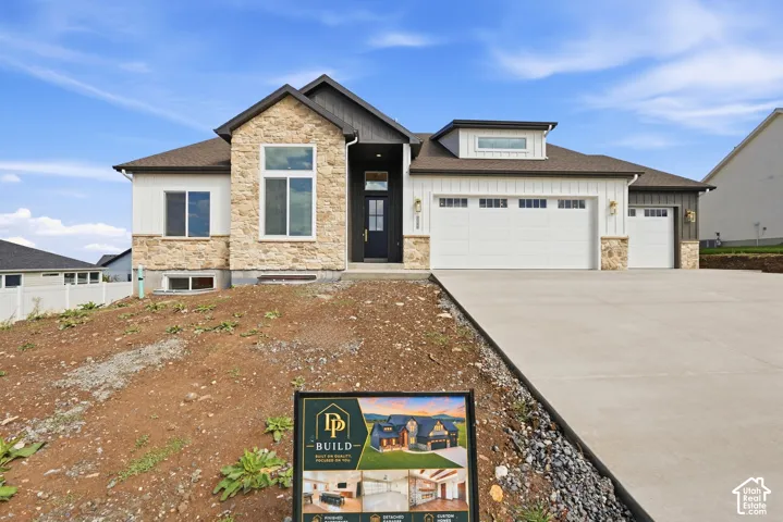 Modern exterior featuring stone and board-and-batten siding, a prominent front entry, and an attached three-car garage