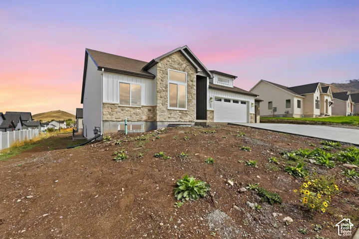 Contemporary home featuring stone and vertical siding accents, an attached garage, and a concrete driveway