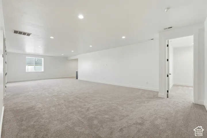 Expansive carpeted room featuring recessed lighting and a window with white trim