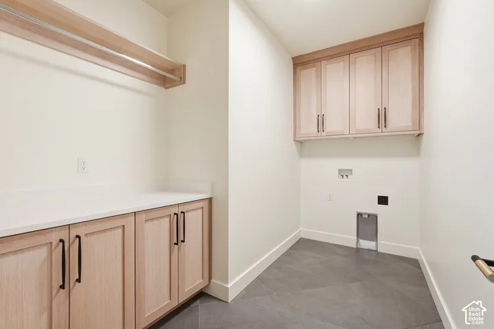 Light wood cabinetry, white countertops, built-in hanging rod, tiled flooring, and overhead lighting