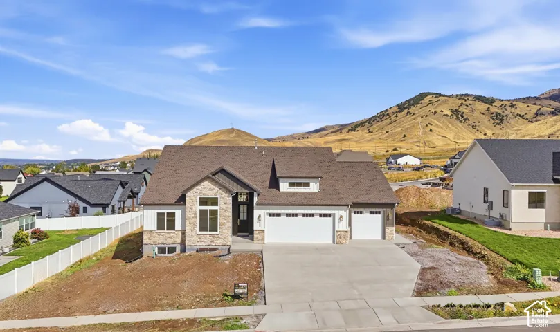 Contemporary residence featuring a stone and siding exterior, a multi-car garage, and a prominent front entry