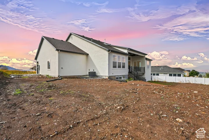 Stucco exterior with multiple windows, covered patio, and outdoor stair access
