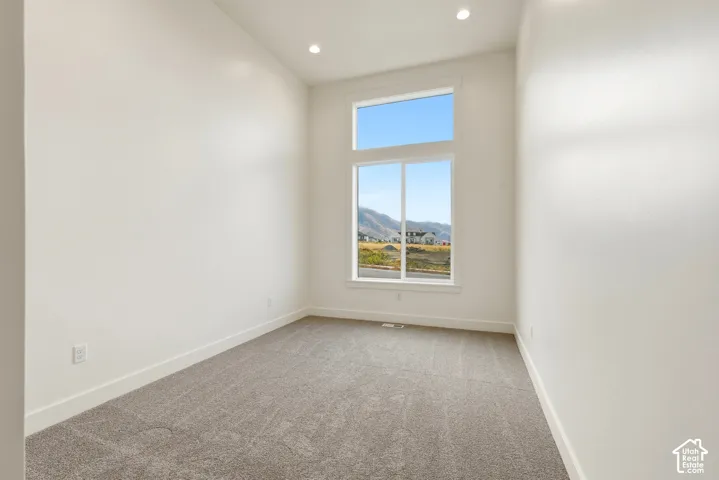 Room featuring a large window, high ceilings, recessed lighting, and neutral carpeting