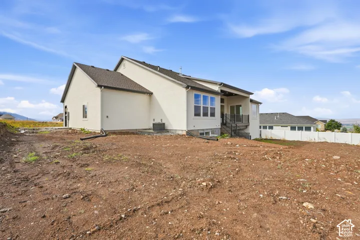 Rear exterior featuring a covered patio, multiple large windows, and a multi-level deck with dark railings