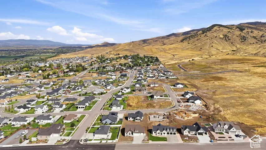 New construction homes with paved driveways and attached garages, situated in a developing community with mountain backdrops