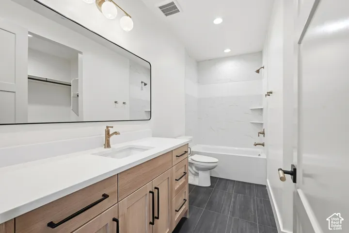 Vanity with wood-finish cabinetry, white countertop, and gold-tone faucet