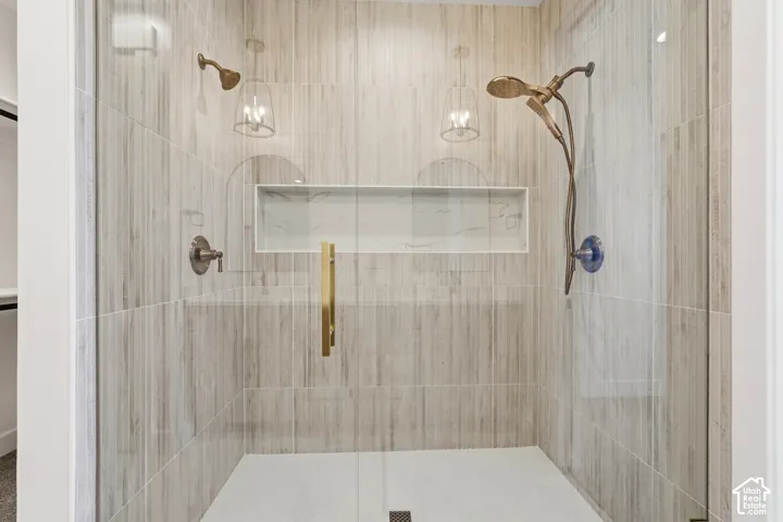 Glass-enclosed shower with full-height vertical tile, dual showerheads, and a recessed niche