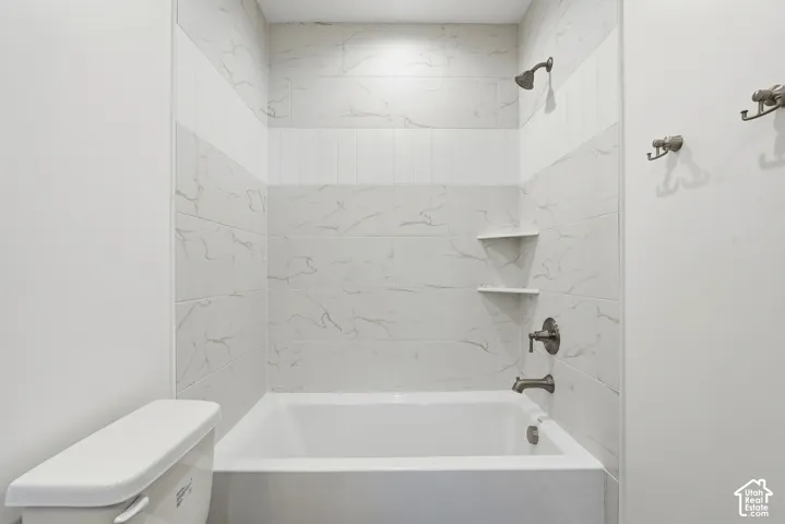 Bathtub with a tiled surround featuring two accent bands, integrated corner shelves, and brushed nickel fixtures