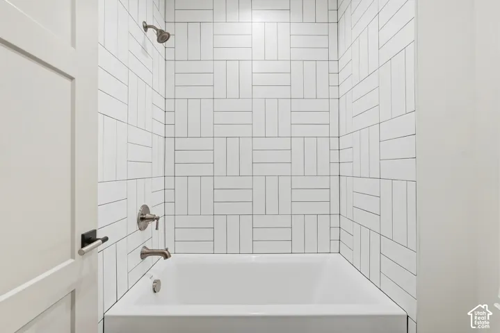 White subway tile surround with a basketweave pattern, integrated bathtub, and brushed nickel fixtures
