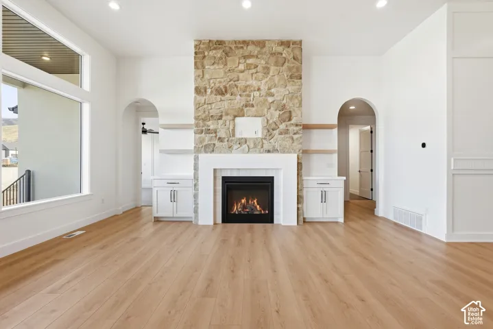Stone-faced fireplace with a white mantel, built-in cabinetry, and wood-finish flooring