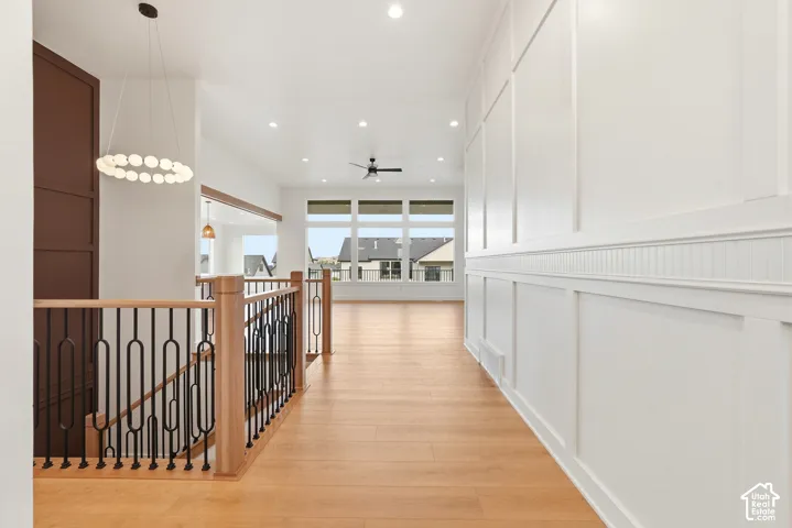 Expansive hallway with wood-finish flooring, staircase with metal balusters, integrated recessed lighting, and large windows