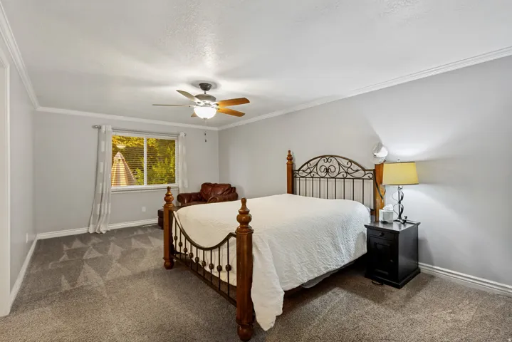 Expansive room with neutral carpeting, a ceiling fan with integrated lighting, and a prominent window with blinds