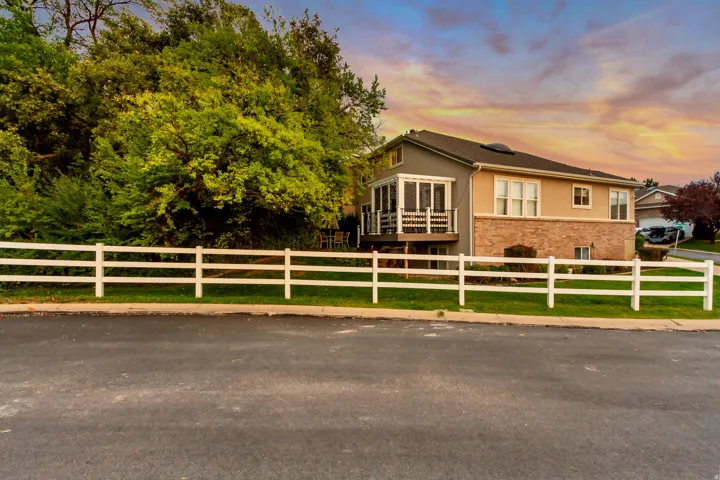 Multi-level exterior featuring a screened-in porch, deck, and a white fence