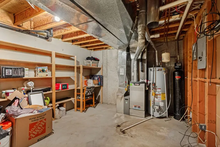 Exposed ceiling joists and ductwork, concrete flooring, and built-in shelving units