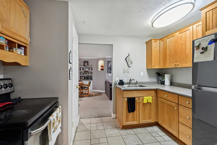 Kitchen featuring wood cabinetry, stainless steel sink, black range, and black refrigerator