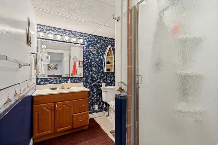 Bathroom featuring a wood vanity with integrated sink, a mirrored medicine cabinet, and a shower with a frosted glass enclosure