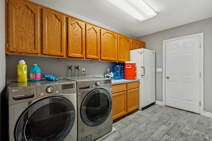 Utility room featuring extensive wood-finish cabinetry, a dedicated counter space, and durable tile flooring