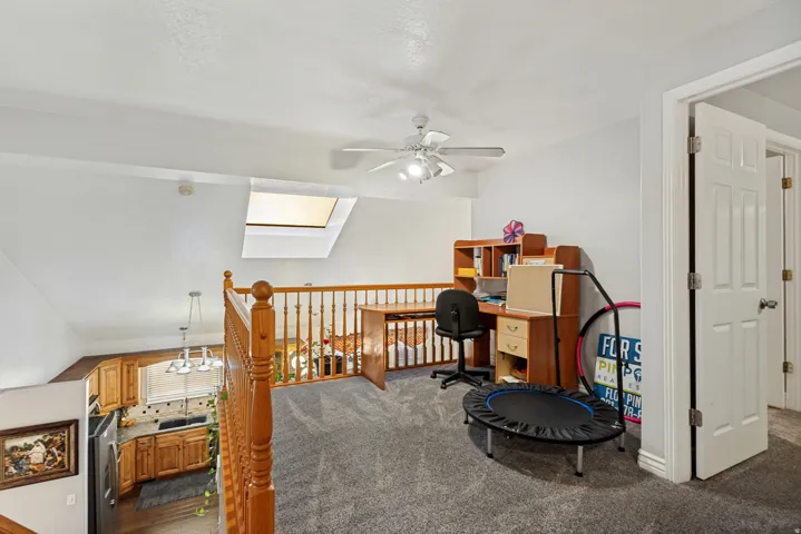 Loft area with a skylight, ceiling fan, and carpeted flooring