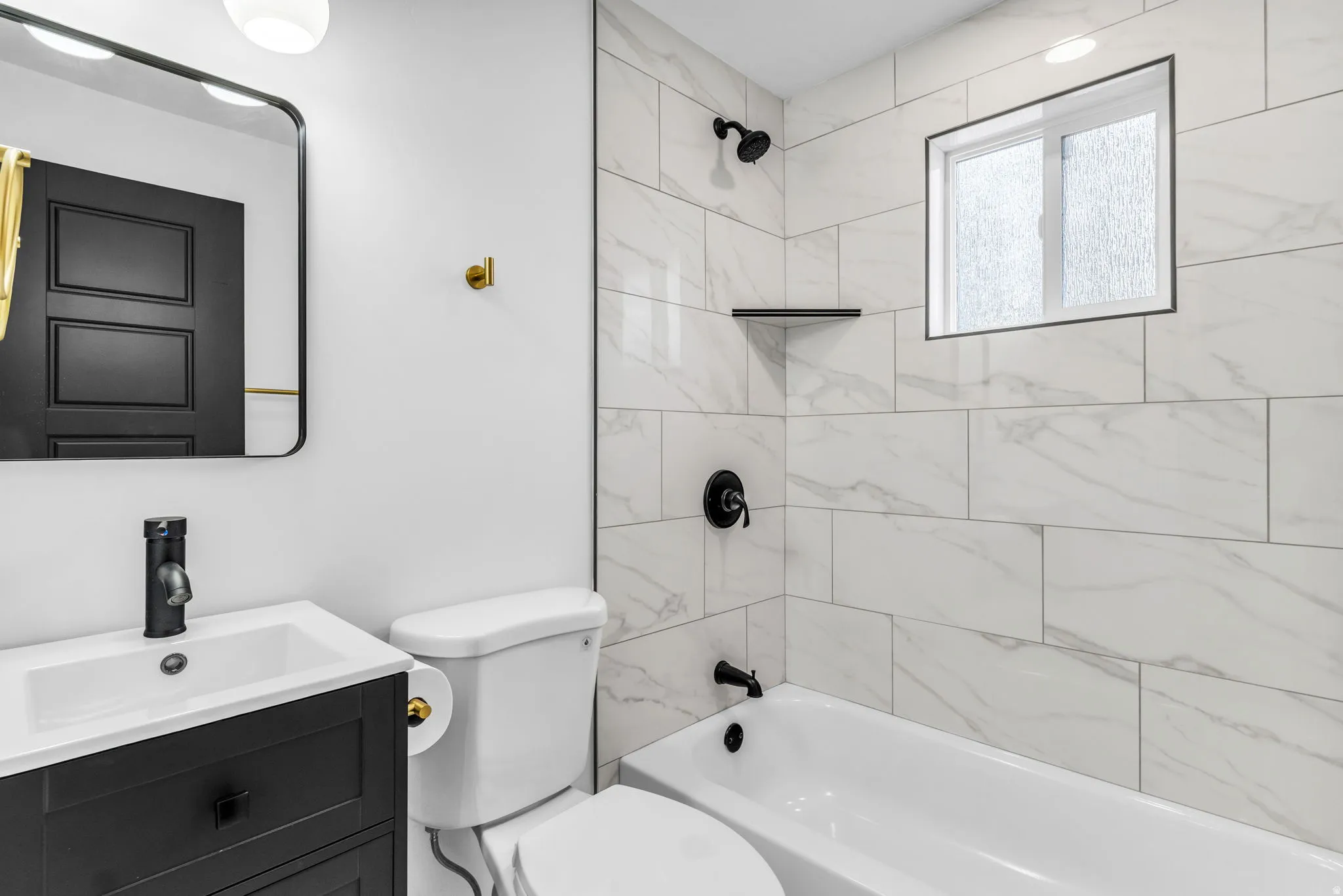 Bathroom featuring a dark wood-finish vanity, white countertop, matte black fixtures, white subway tile shower surround, and a built-in shower shelf