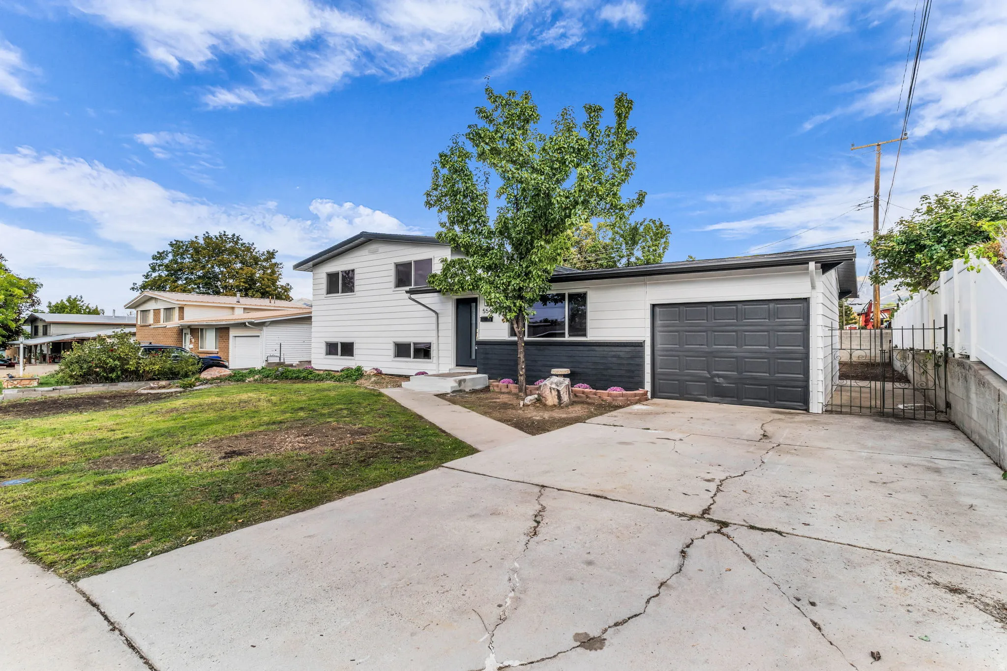 Split-level residence featuring a two-tone exterior, attached garage, and a concrete driveway
