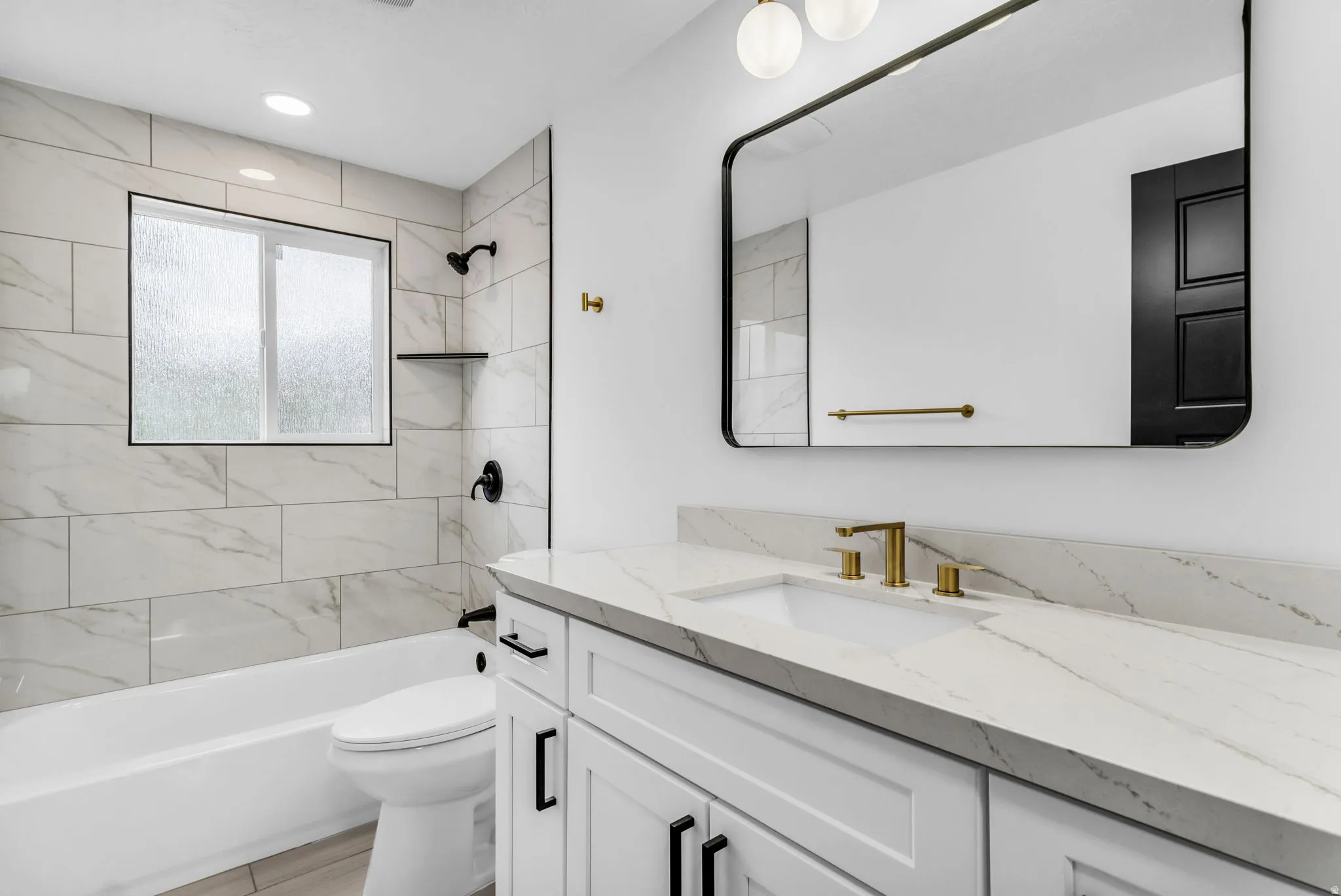 White vanity with a light-toned countertop, gold-finish faucet, and a rectangular mirror