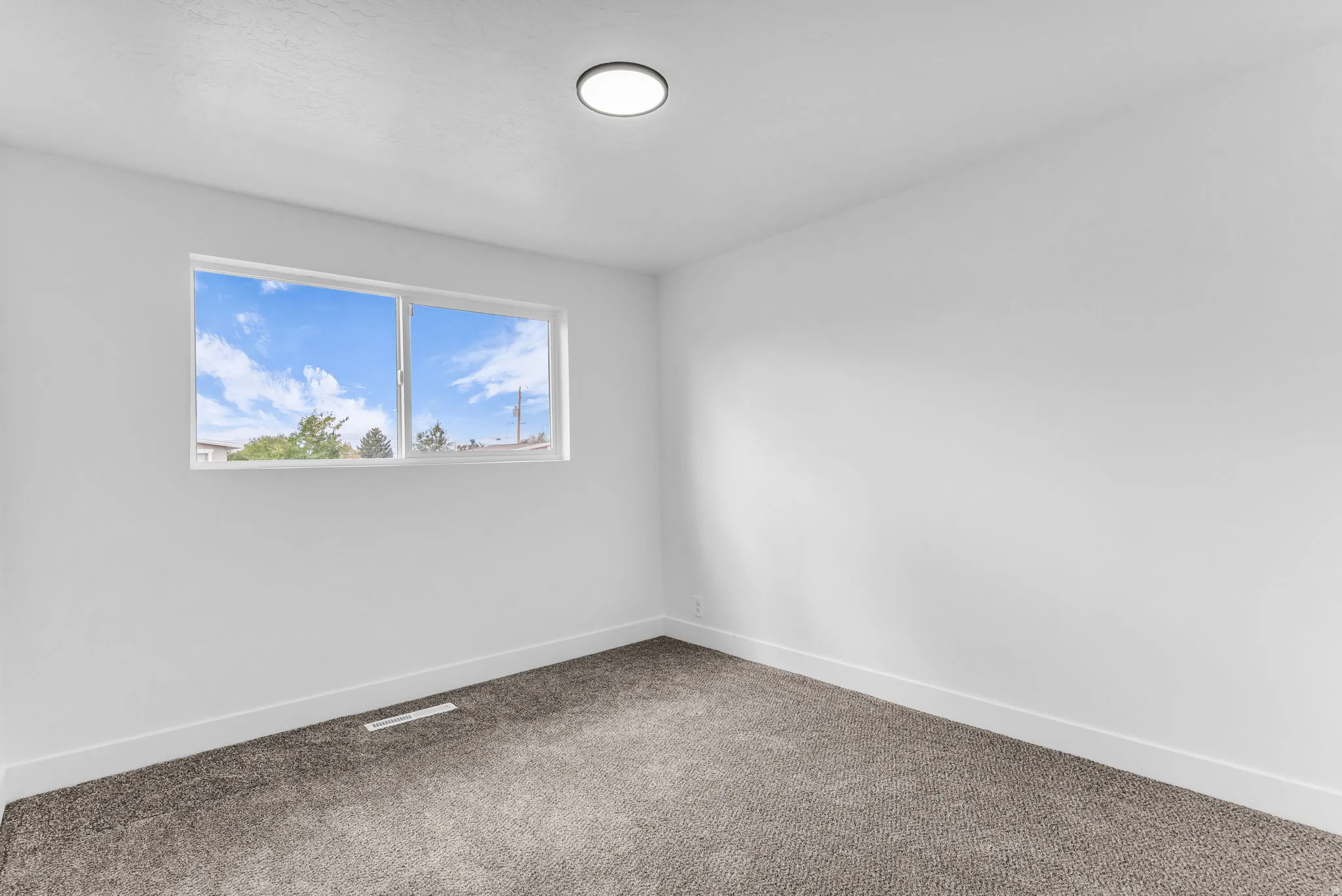 Neutral color palette with textured carpeting, a white trim package, and a contemporary flush-mount ceiling light