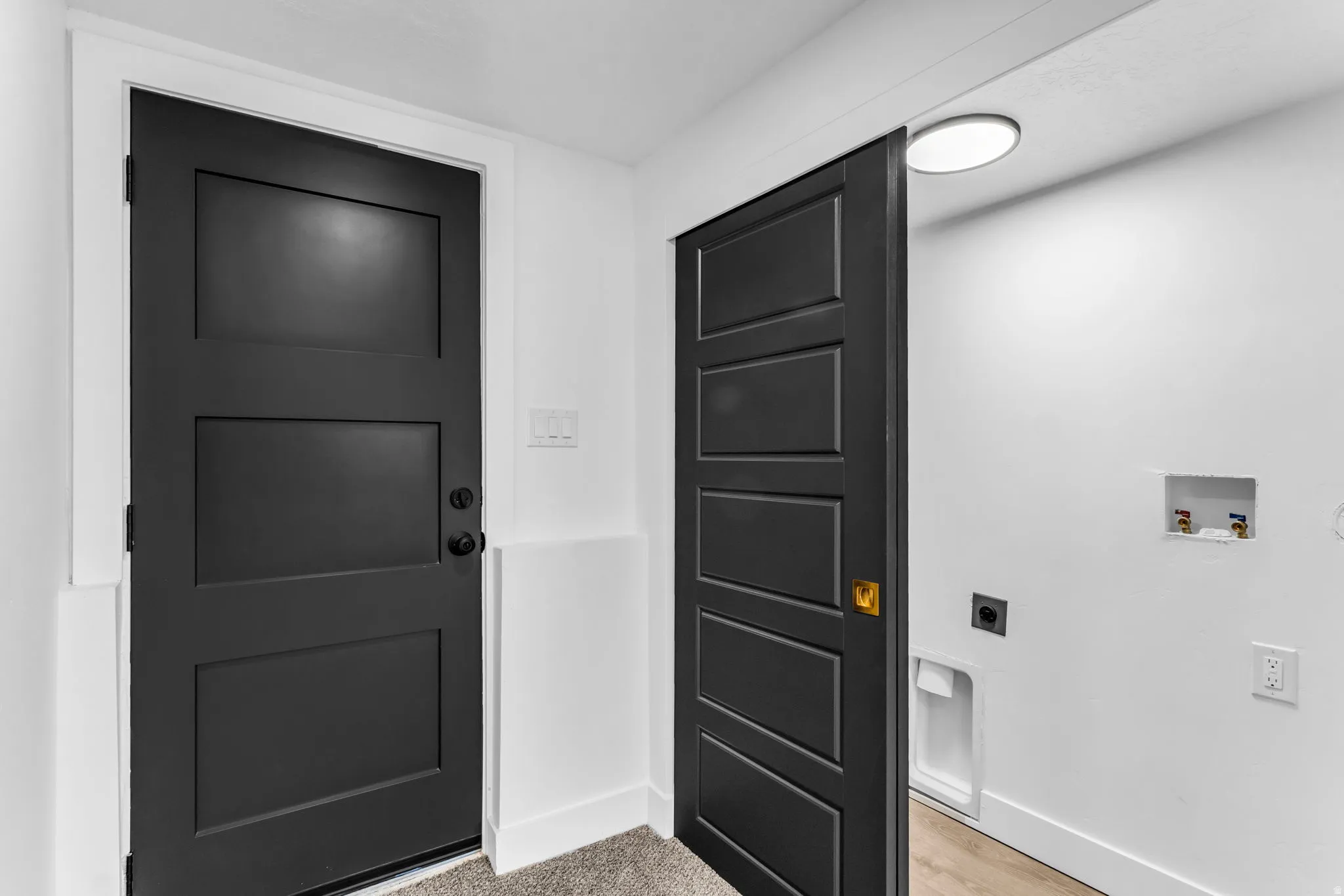 Three-panel interior door with matte black hardware, white wall finishes, and recessed ceiling lighting