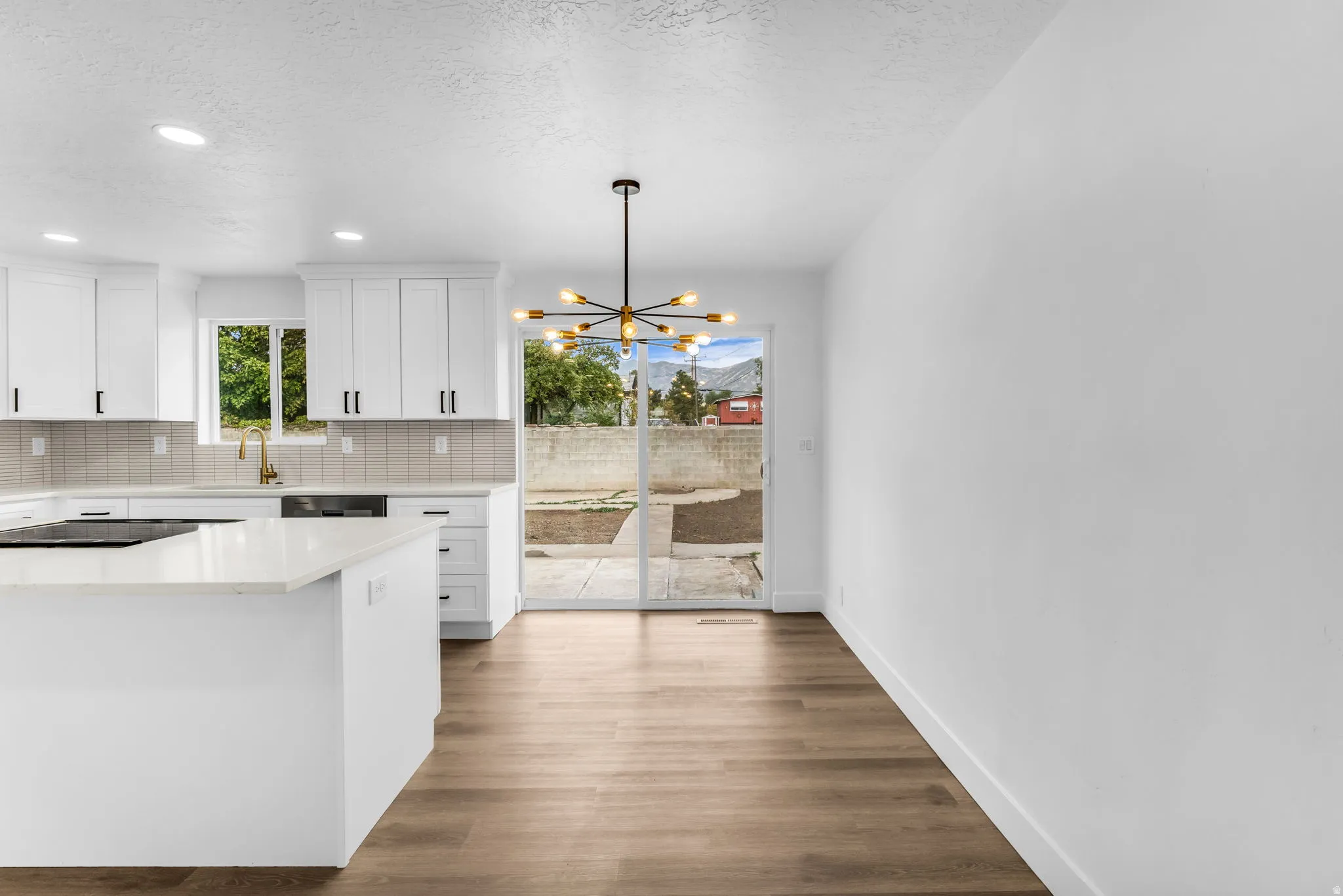 Kitchen featuring white cabinetry, quartz countertops, a tile backsplash, and wood-finish flooring