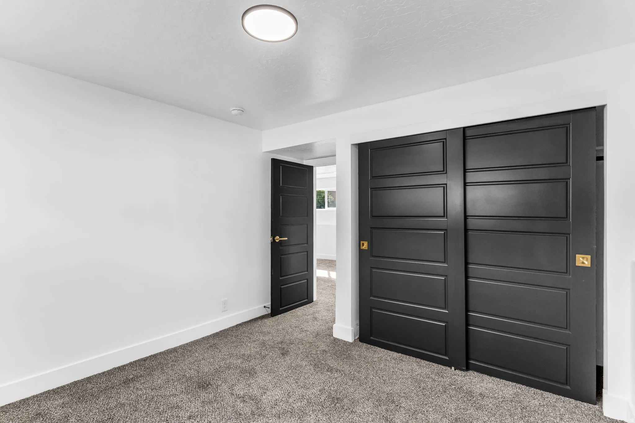 Gray carpeted flooring, white walls, and a flush mount ceiling light