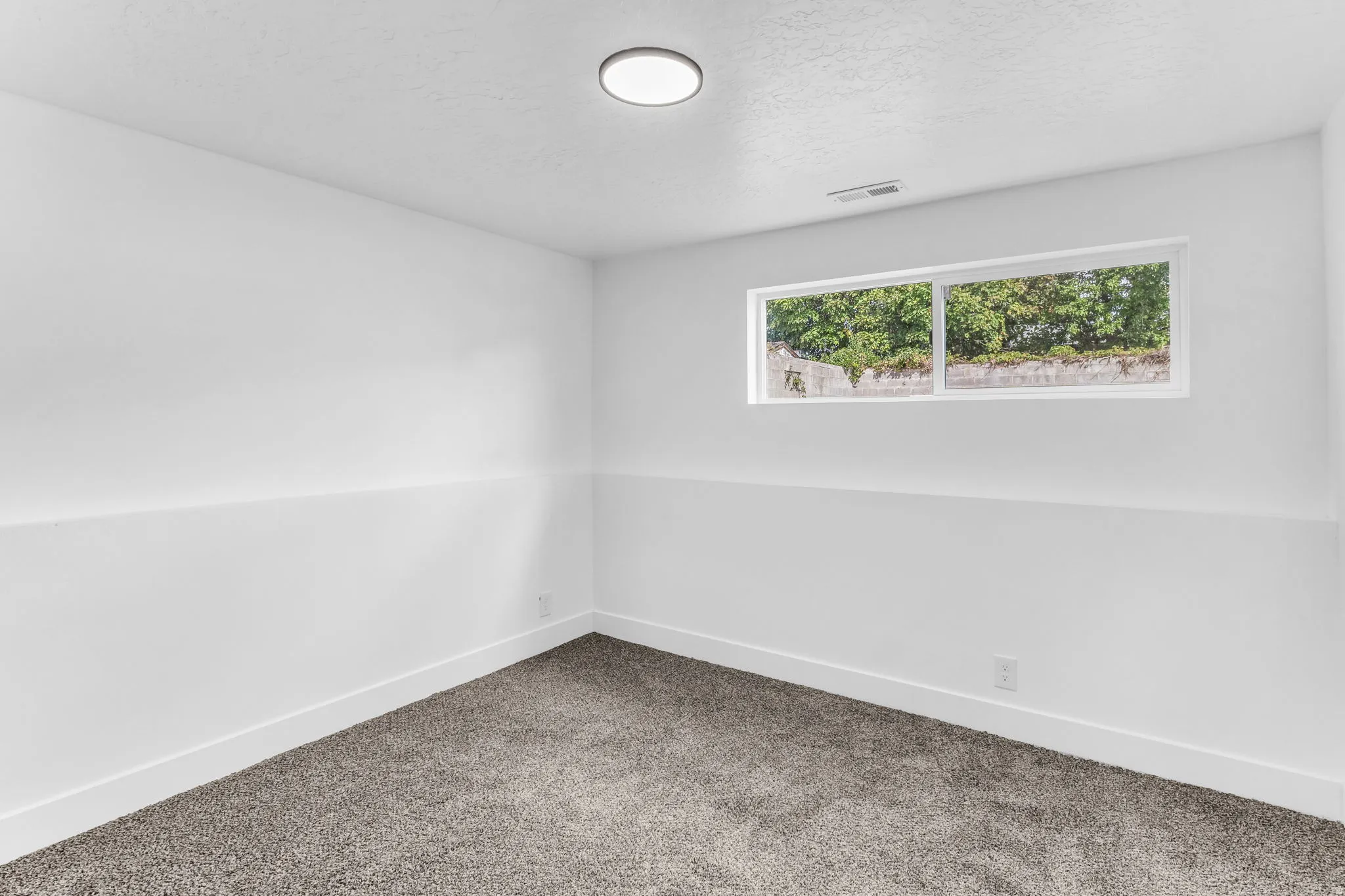 Recessed lighting, white walls, gray carpet, and a horizontal window