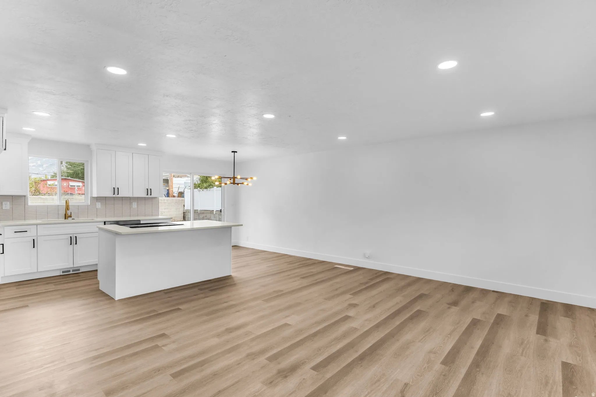 Spacious open-concept layout with wood-finish flooring, recessed lighting, and a kitchen island with stone-finish countertop