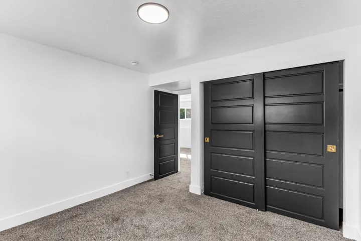 Gray carpeted flooring, white walls, and a flush mount ceiling light