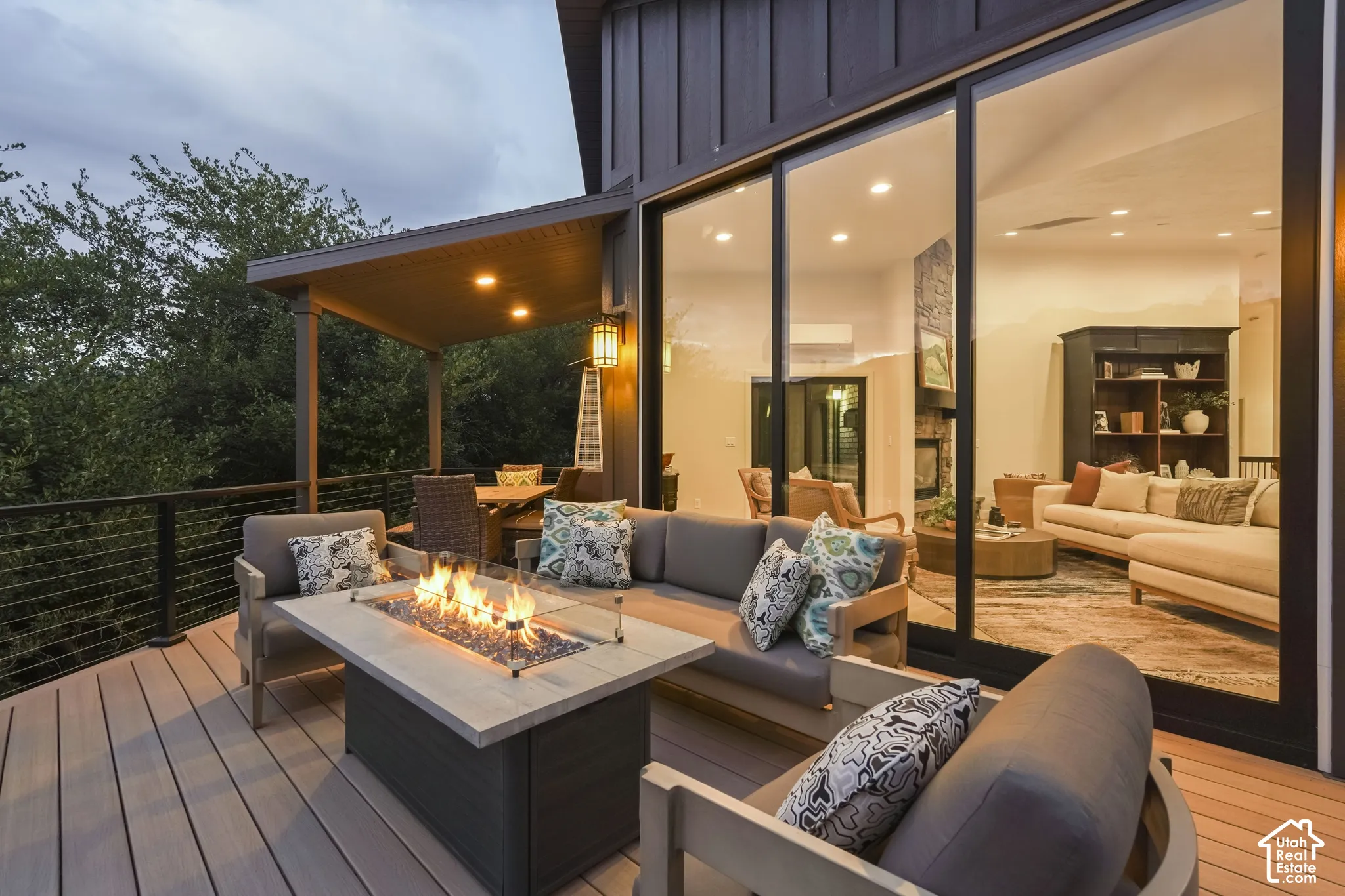 Spacious outdoor deck with a built-in fire pit, covered dining area, and wire railing