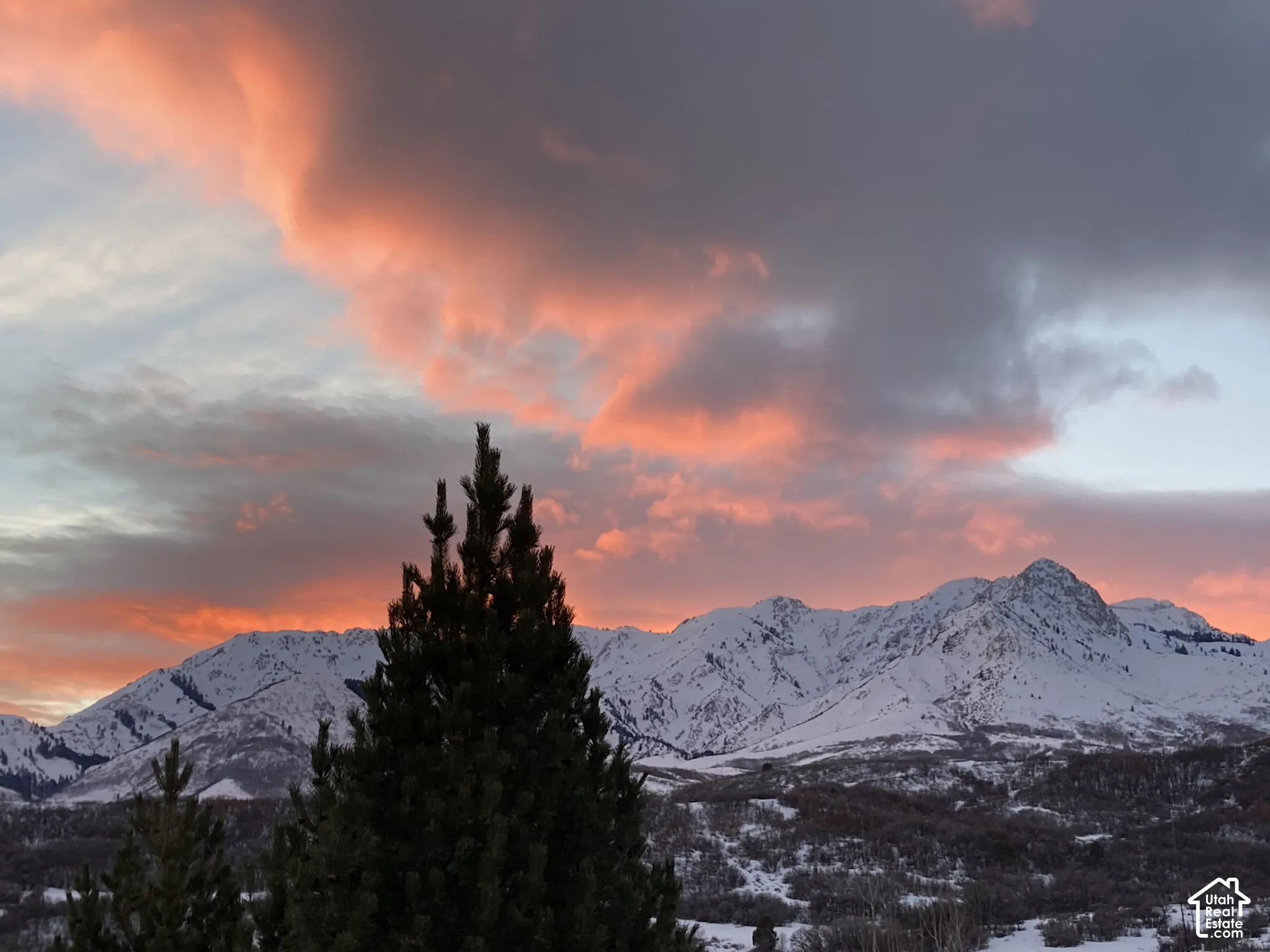 Snow-capped mountain range with a prominent peak, framed by a vibrant sunset sky