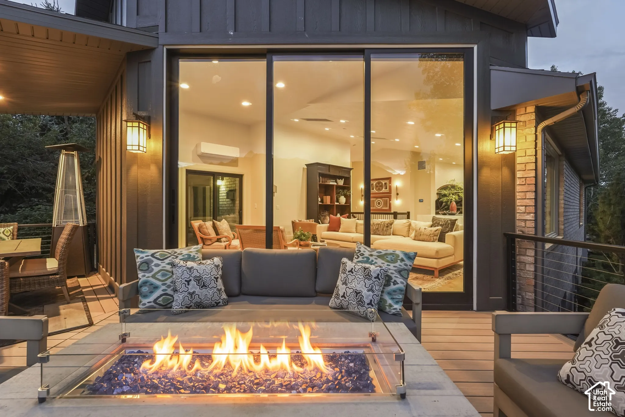 Expansive outdoor deck with a built-in fire pit, glass safety barrier, and wood-finish flooring