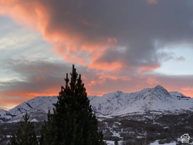 Snow-capped mountain range with a prominent peak, framed by a vibrant sunset sky