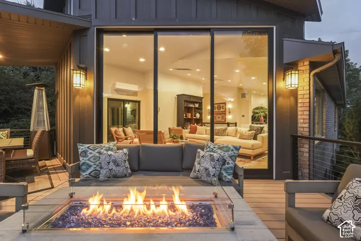 Expansive outdoor deck with a built-in fire pit, glass safety barrier, and wood-finish flooring