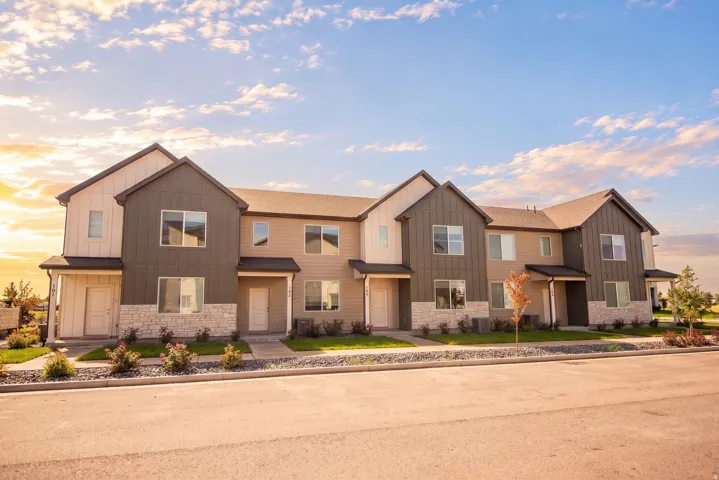 Contemporary multi-family building featuring mixed-material siding, stone accents, multiple large windows, and individual covered entryways