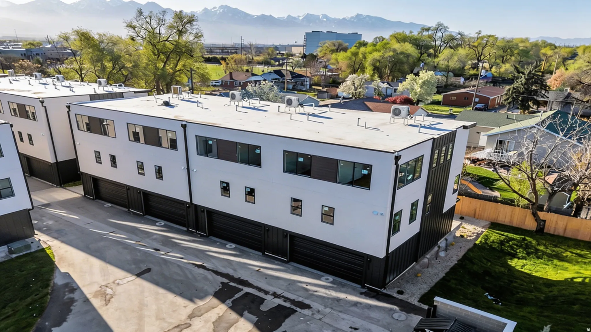 Contemporary multi-level townhome featuring a white and dark gray exterior, flat roof, and a private garage