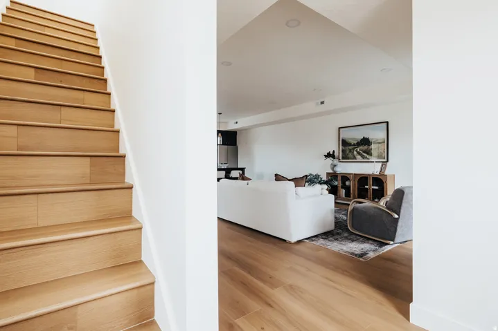Light wood-finish flooring throughout, bright white walls, recessed ceiling lighting, open-concept design, and a light wood-finish staircase
