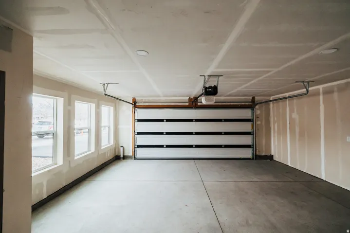 Spacious garage with multiple windows, concrete flooring, and a paneled garage door with an automatic opener