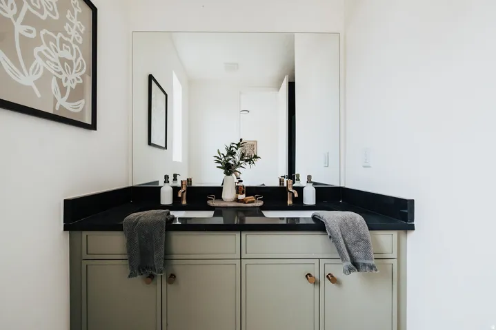 Dual undermount sinks with brushed brass faucets, set within a dark countertop and backsplash