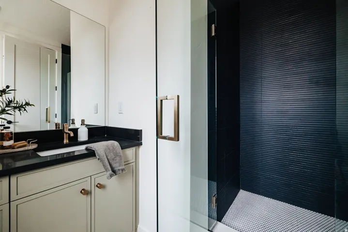 Built-in vanity with integrated sink, dark countertop, and gold-finish hardware